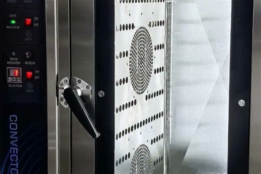 Side-mounted blower with perforated stainless steel air guide inside GLEAN commercial convection oven driving hot air circulation across baking trays