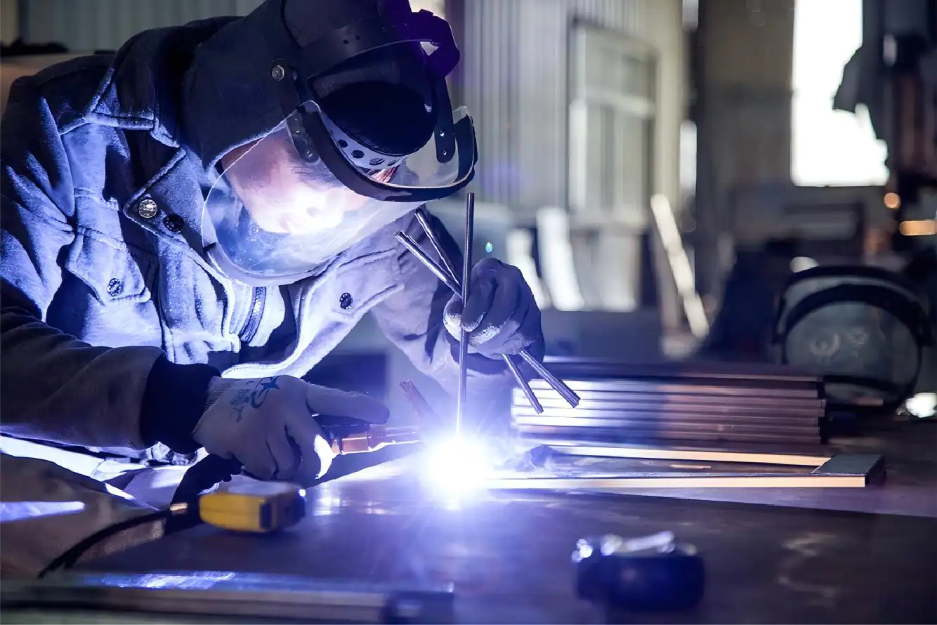 A skilled welder performing precision arc welding on stainless steel components at GLEAN's anchor manufacturing partner facility in Nanhai District, Foshan.